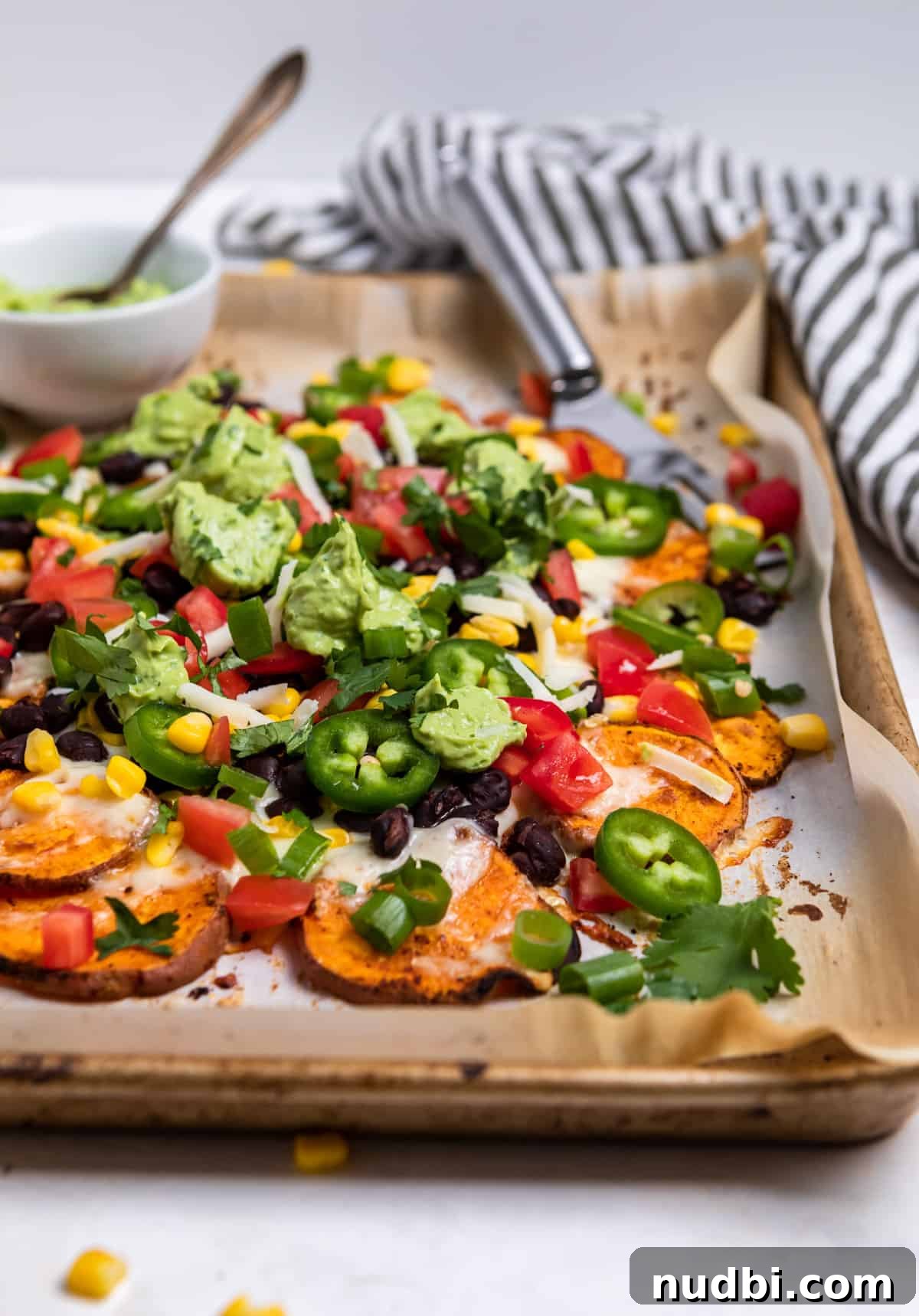 Sweet Potato Nachos with Creamy Avocado Sauce 2 Sheet pan with sweet potato nachos topped with beans, corn, cilantro and avocado crema.