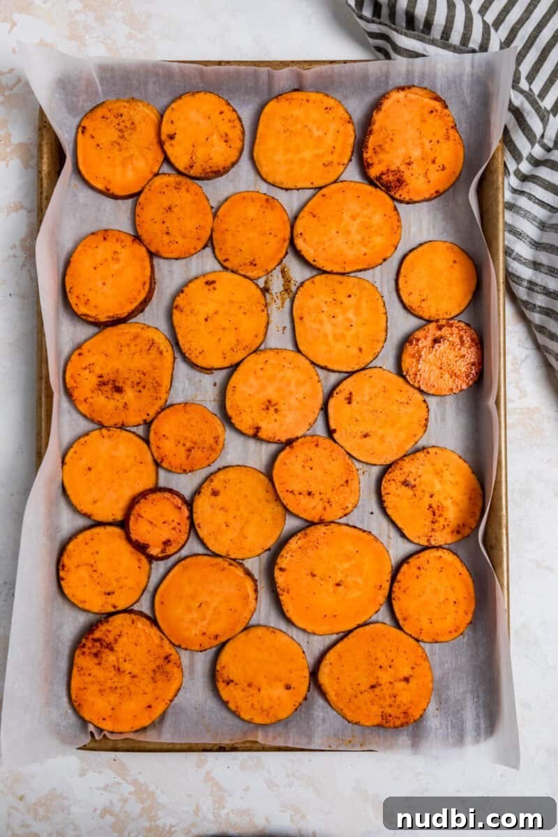 Sweet Potato Nachos with Creamy Avocado Sauce 4 Seasoned sweet potato slices on parchment lined sheet pan.
