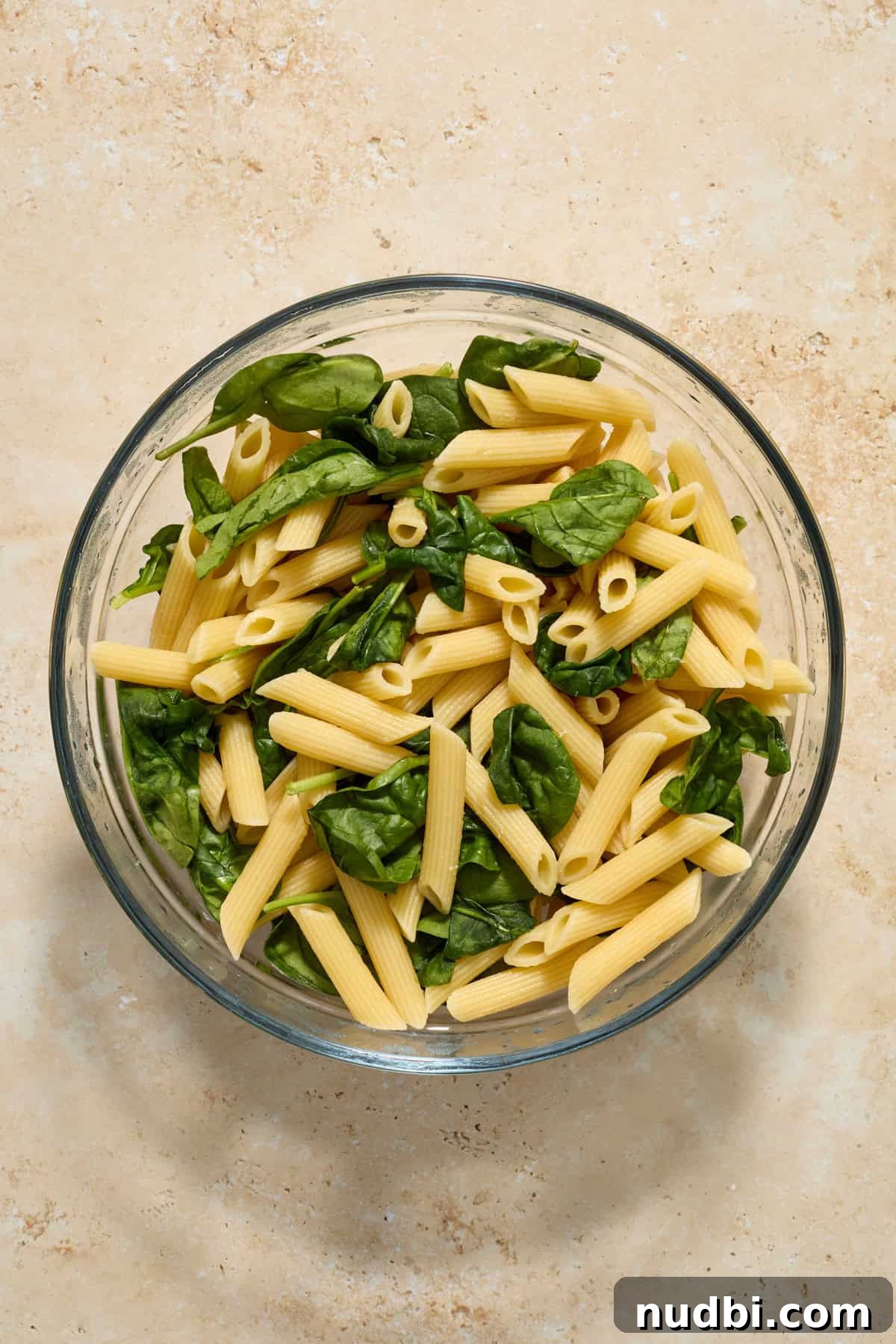 Sun-Dried Tomato Pasta with Italian Sausage Recipe 6 Pasta in glass bowl with spinach.
