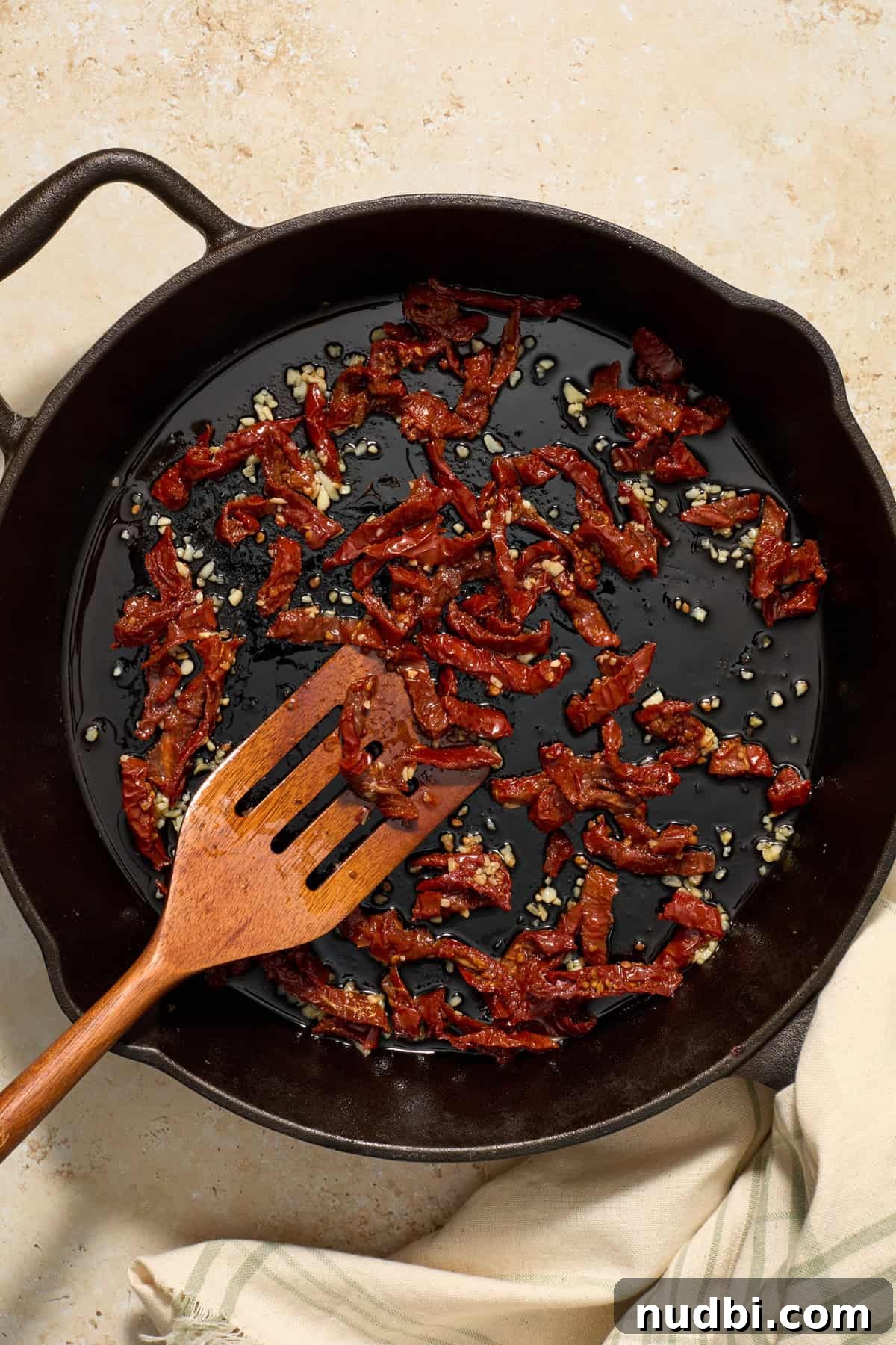 Sun-Dried Tomato Pasta with Italian Sausage Recipe 7 Sun-dried tomatoes and garlic in skillet with wood slotted spoon.