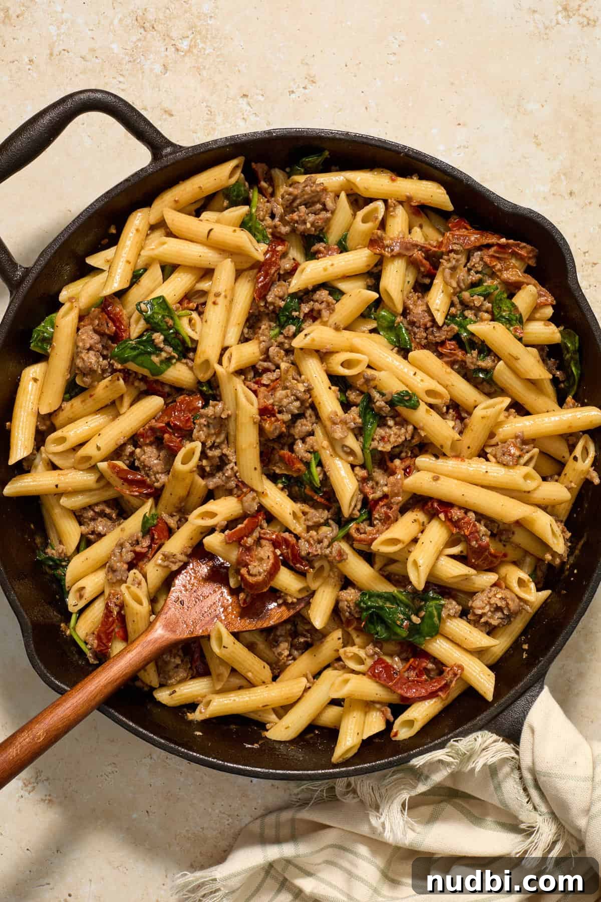 Sun-Dried Tomato Pasta with Italian Sausage Recipe 10 Sun-dried tomato and Italian sausage pasta tossed together with wood spoon in cast iron skillet.