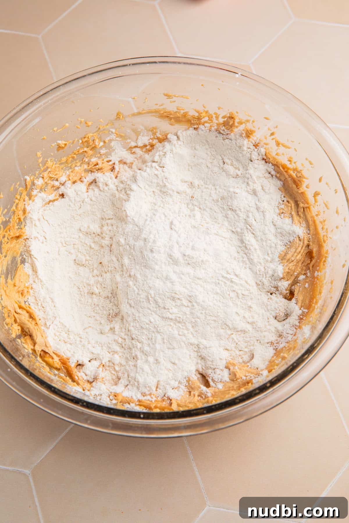 Edible Peanut Butter Cookie Dough Recipe for Safe Snacking 5 Flour added to peanut butter cookie dough mixture in bowl.
