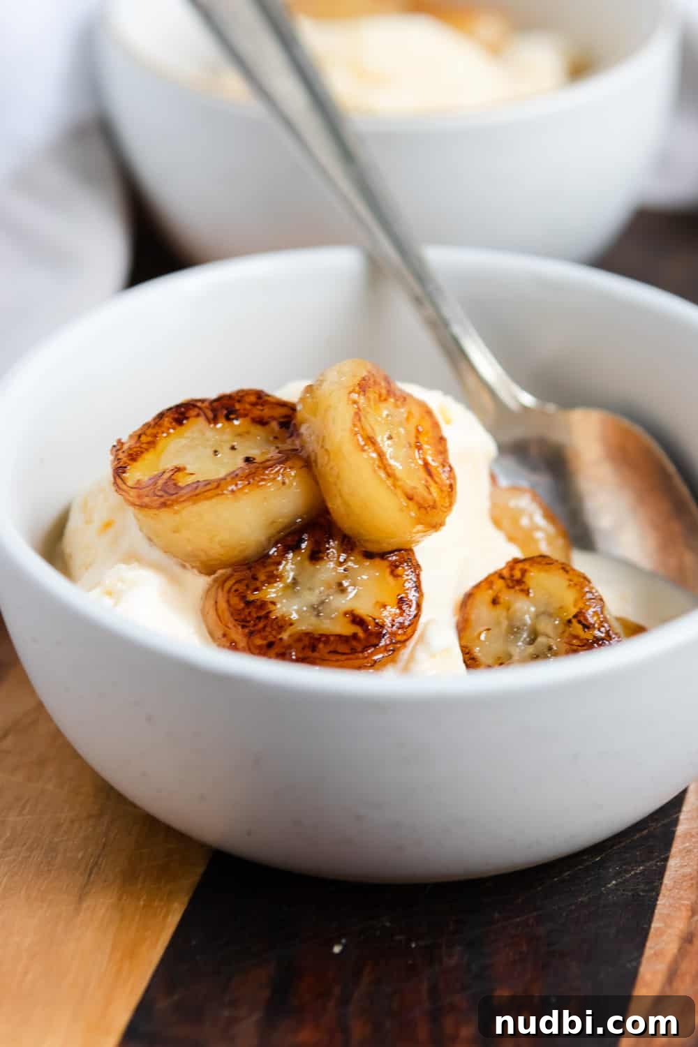 Maple Fried Bananas in 5 Minutes — Quick Breakfast or Dessert 3 Fried bananas in bowl with vanilla ice cream and spoon.