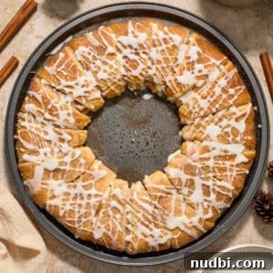 Cinnamon Crescent Roll Wreath Recipe — Festive Holiday Pastry 16 Cinnamon crescent wreath on pan with icing drizzle over top.