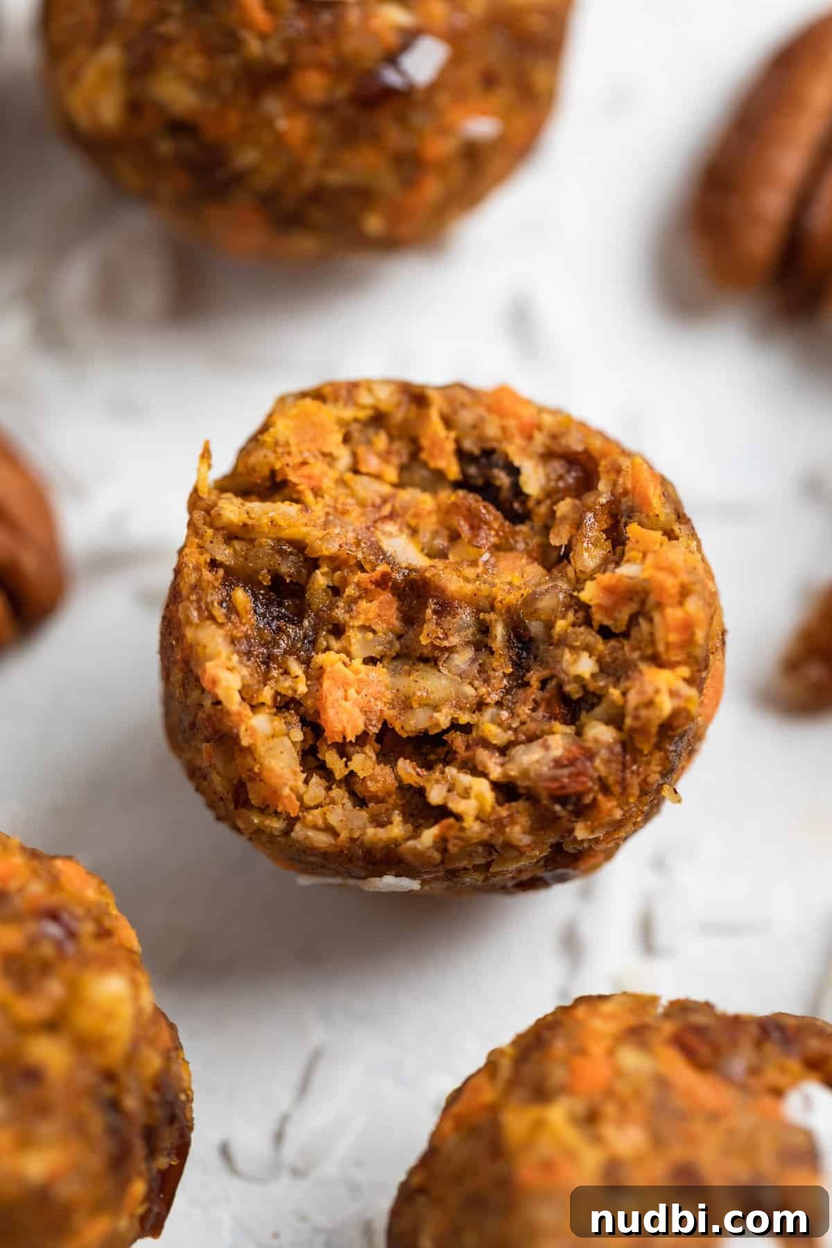 Carrot Cake Bites Recipe: Moist Mini Carrot Cake Balls 2 Carrot cake bites with bite taken out of one and shredded coconut around.