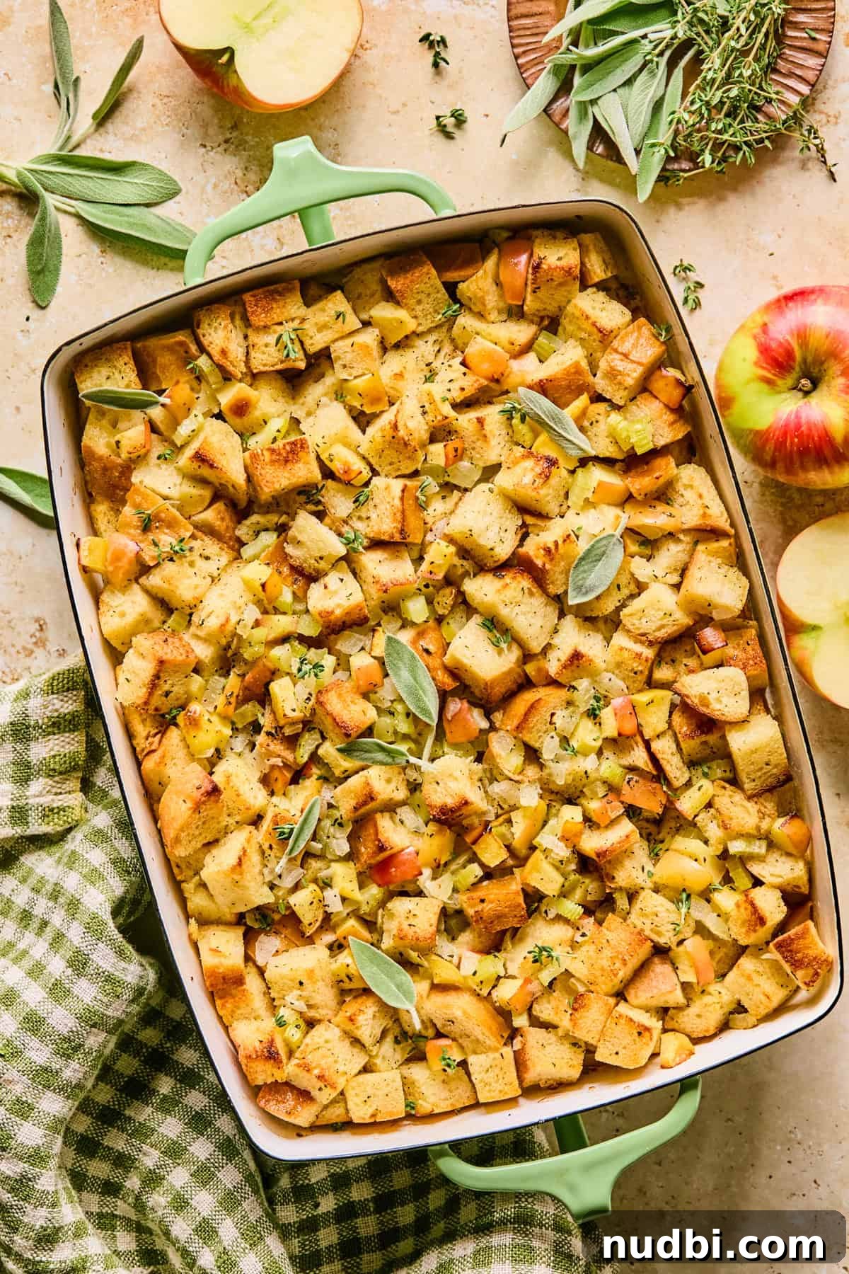 Apple and Sage Stuffing with Cranberries and Pecans 2 Apple stuffing in baking pan with chopped herbs and fresh sage on top.
