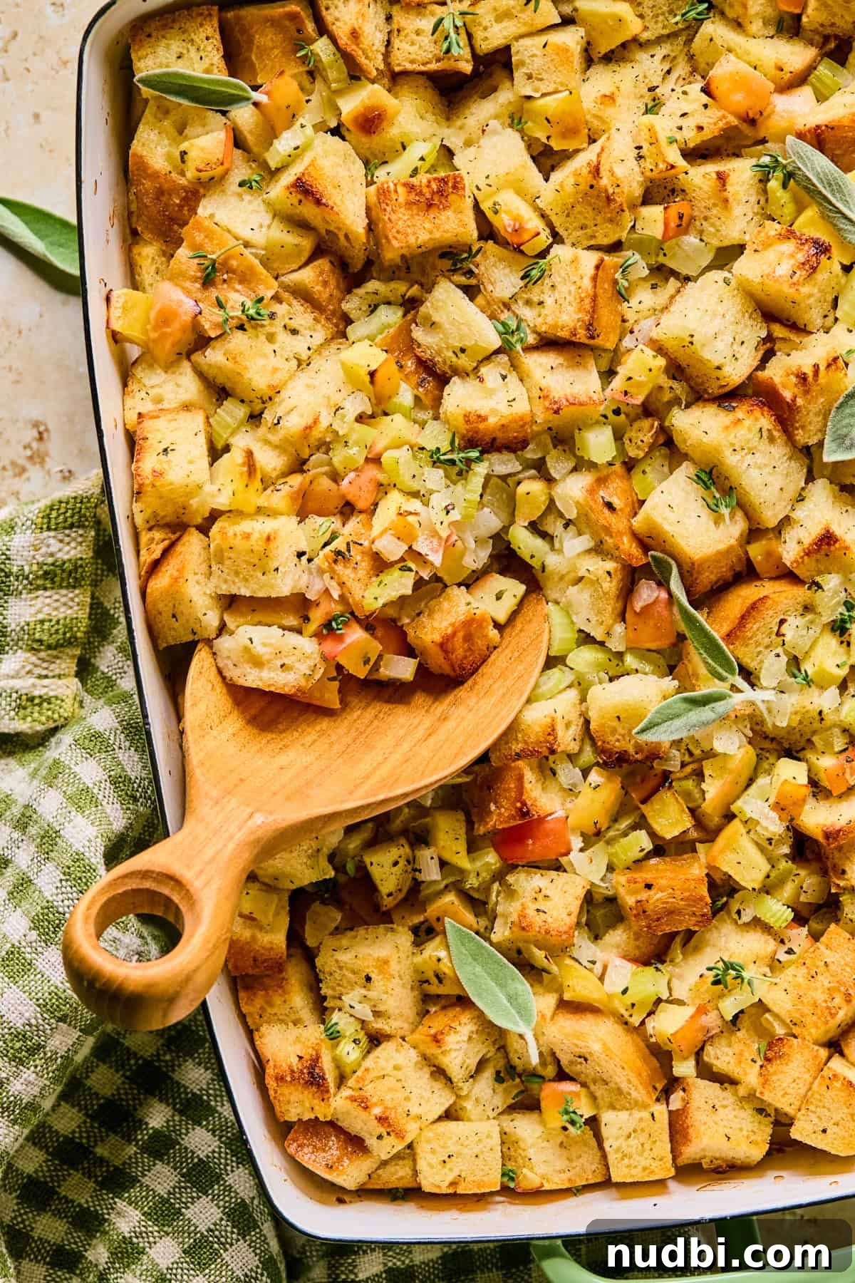 Apple and Sage Stuffing with Cranberries and Pecans 13 Pan with apple stuffing topped with freshly chopped parsley and spoon scooping into the dish.