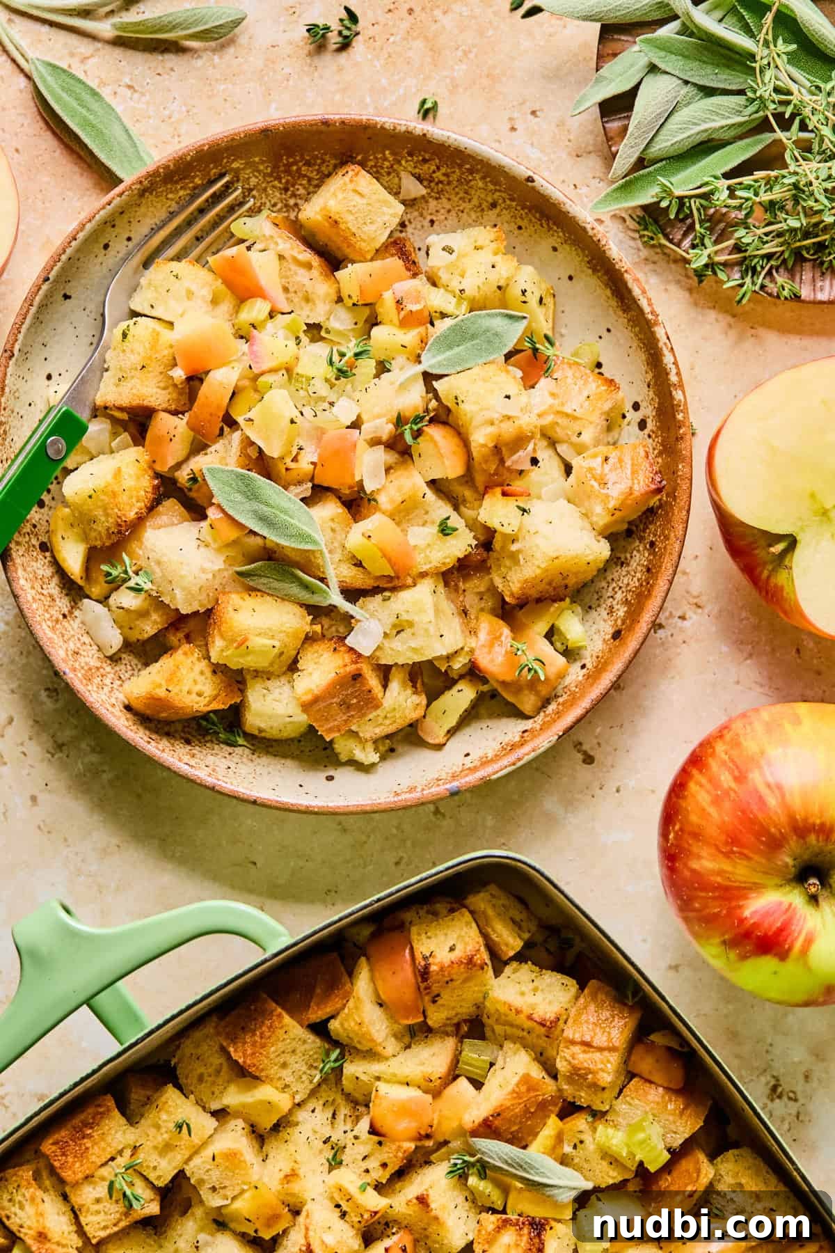 Apple and Sage Stuffing with Cranberries and Pecans 14 Serving of apple sage bread stuffing on plate with pan nearby.
