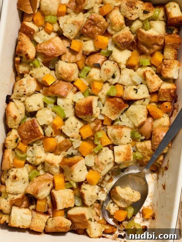 Apple and Sage Stuffing with Cranberries and Pecans 17 Butternut squash stuffing in pan with serving spoon scooping into the dish.