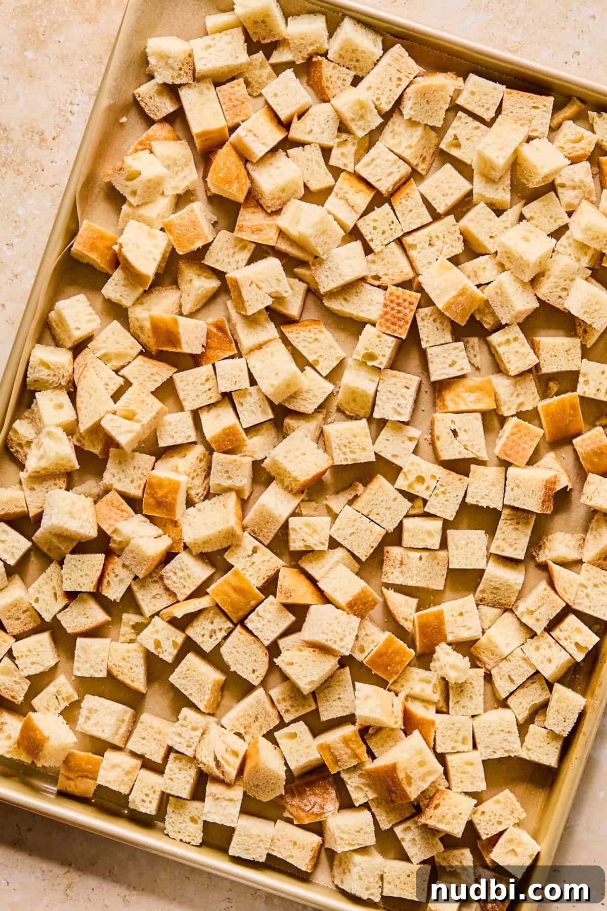 Apple and Sage Stuffing with Cranberries and Pecans 5 Bread cubes on sheet pan.