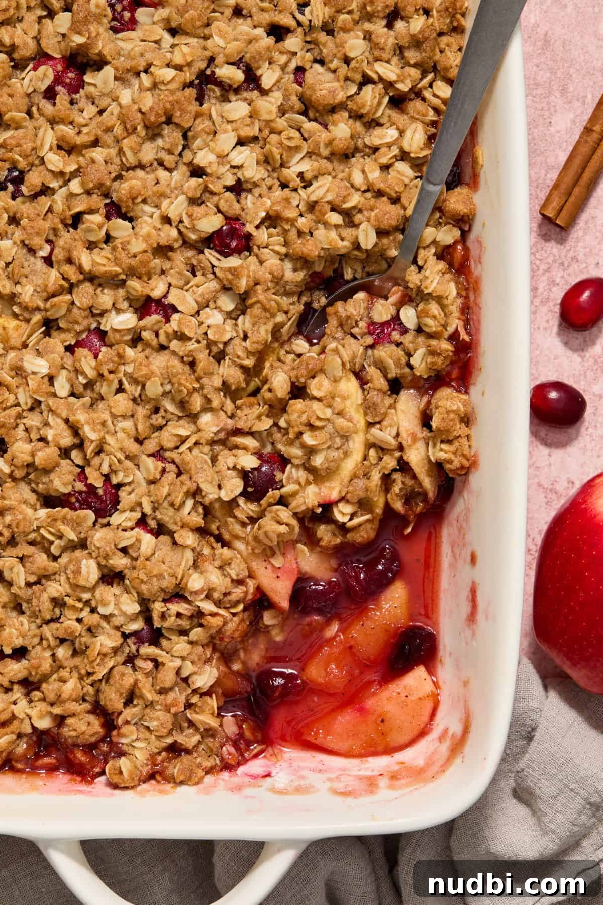 Cranberry Apple Crisp Recipe — Tart & Spiced Autumn Dessert 8 Spoon scooping into dish with baked apple cranberry crisp.