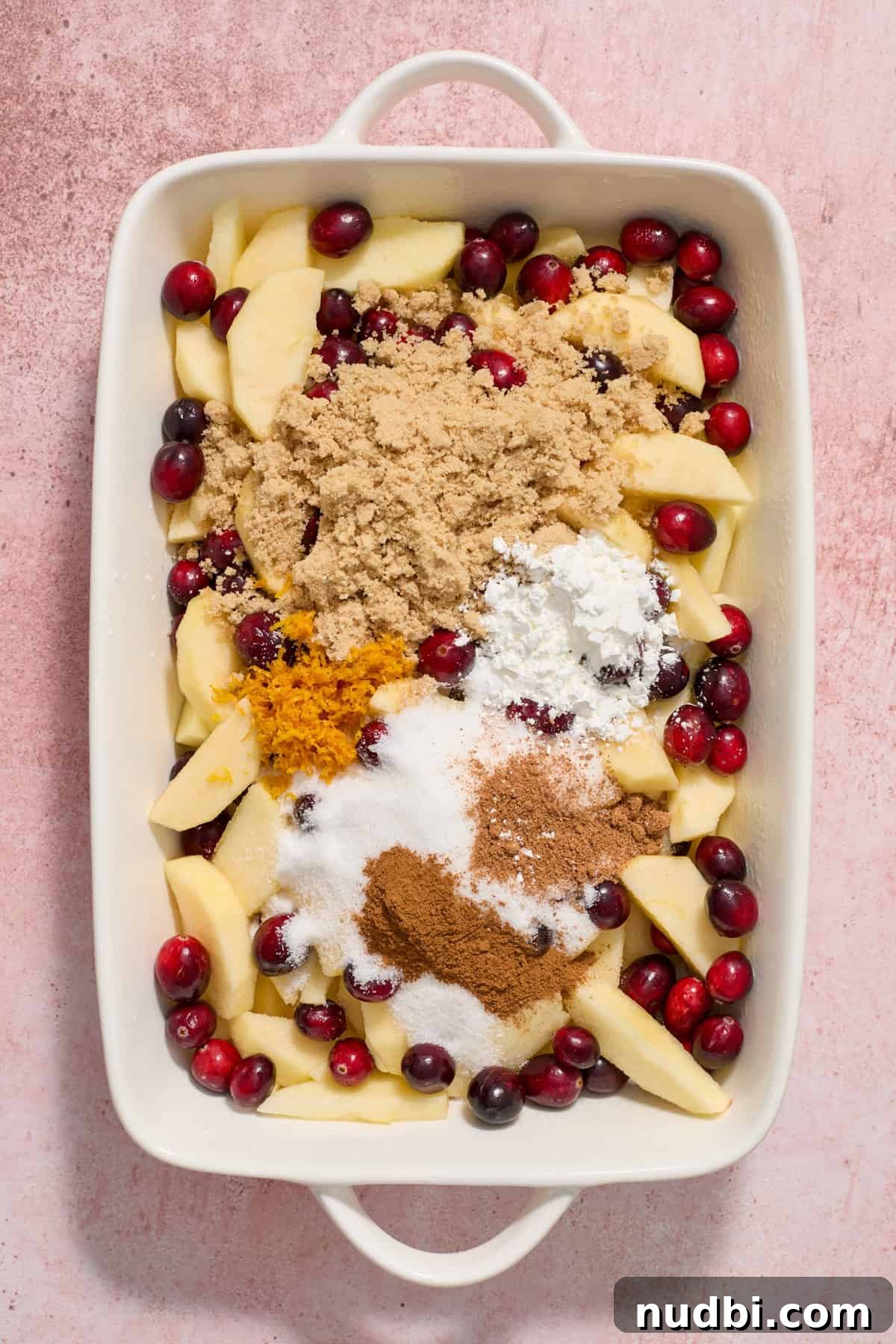 Cranberry Apple Crisp Recipe — Tart & Spiced Autumn Dessert 5 Cranberries, apples, cinnamon, orange zest, sugar and other ingredients in baking dish.