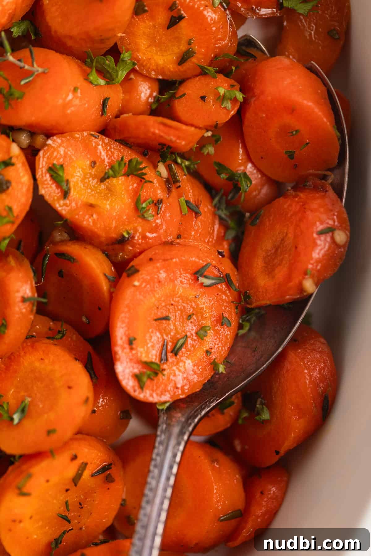 Maple-Glazed Herb-Roasted Carrots with Garlic and Thyme 4 Maple glazed herb roasted carrots in white serving dish topped with fresh parsley and thyme.