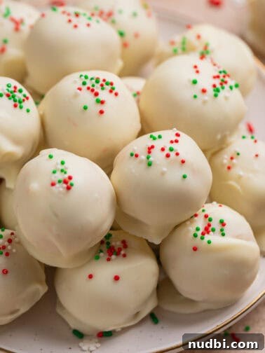 Plate with white chocolate covered Christmas Oreo cookie truffles topped with red, white and green sprinkles.