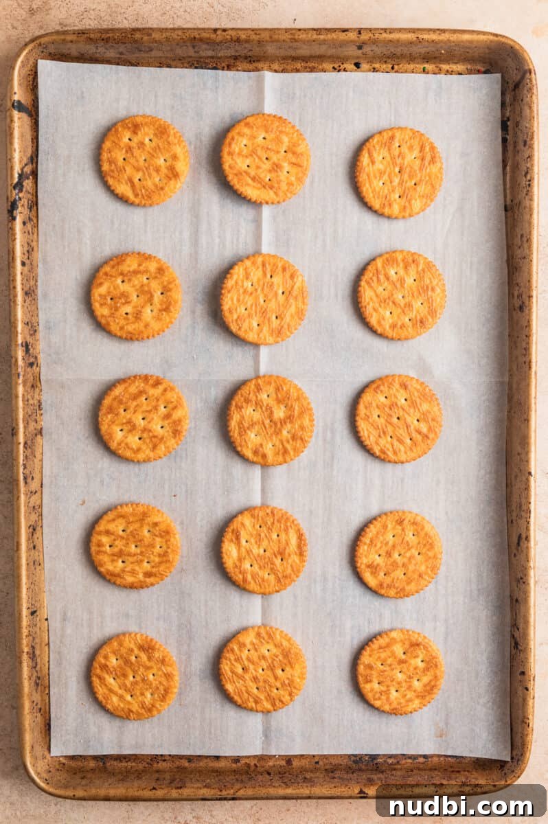 White Chocolate-Dipped Nutella Ritz Cracker Cookies 5 Ritz crackers arranged on parchment paper lined cookie sheet.
