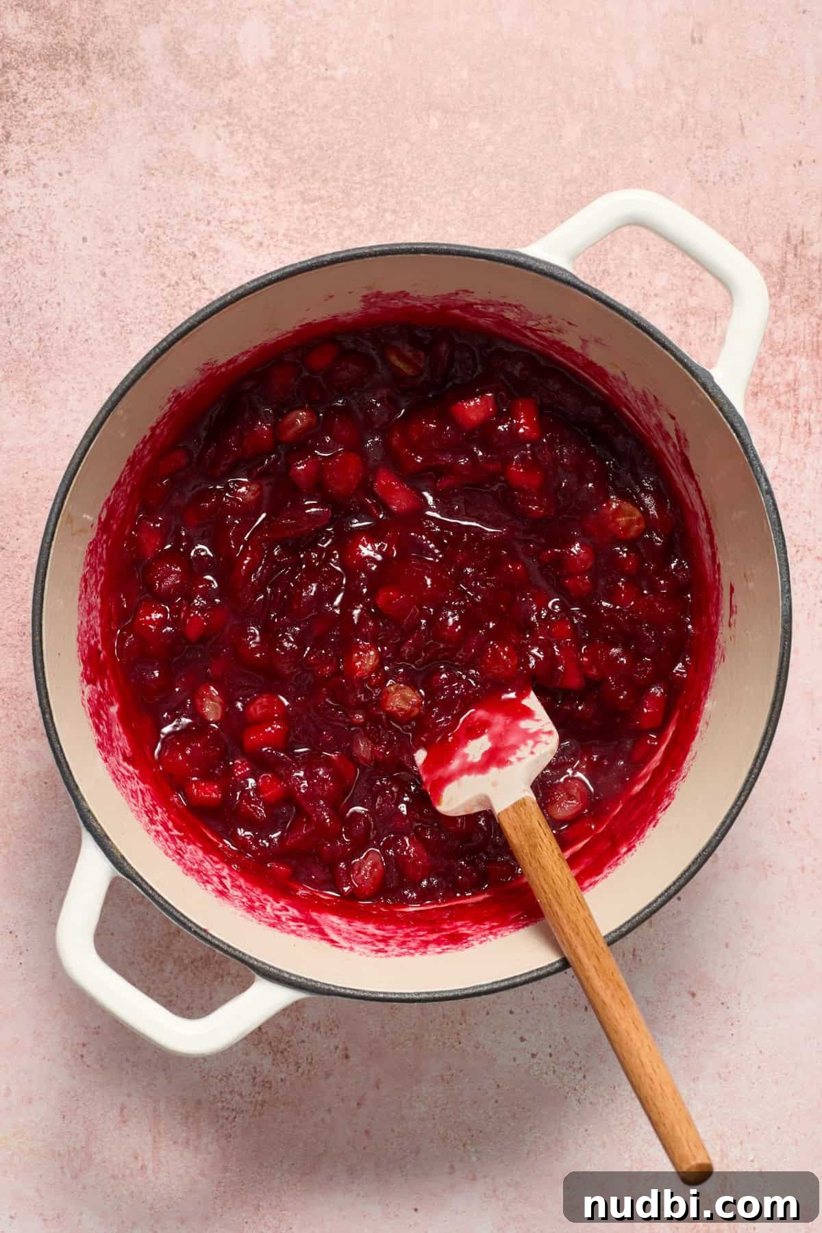 Cranberry Brie Crostini Recipe for Holiday Appetizers 5 Simmering cranberry chutney in a pot with wooden handled spatula stirring.