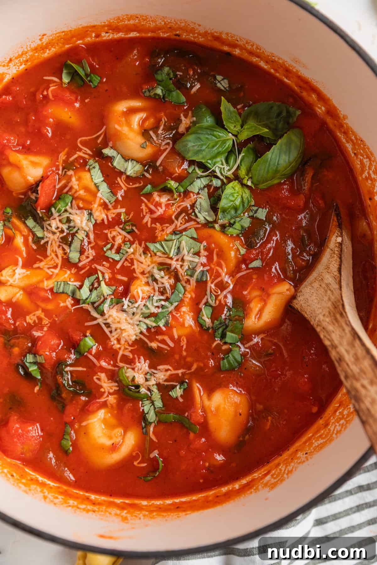 Creamy Tomato Tortellini Soup Recipe for Cozy Dinners 5 Dutch oven with tomato tortellini soup and wooden spoon scooping in.