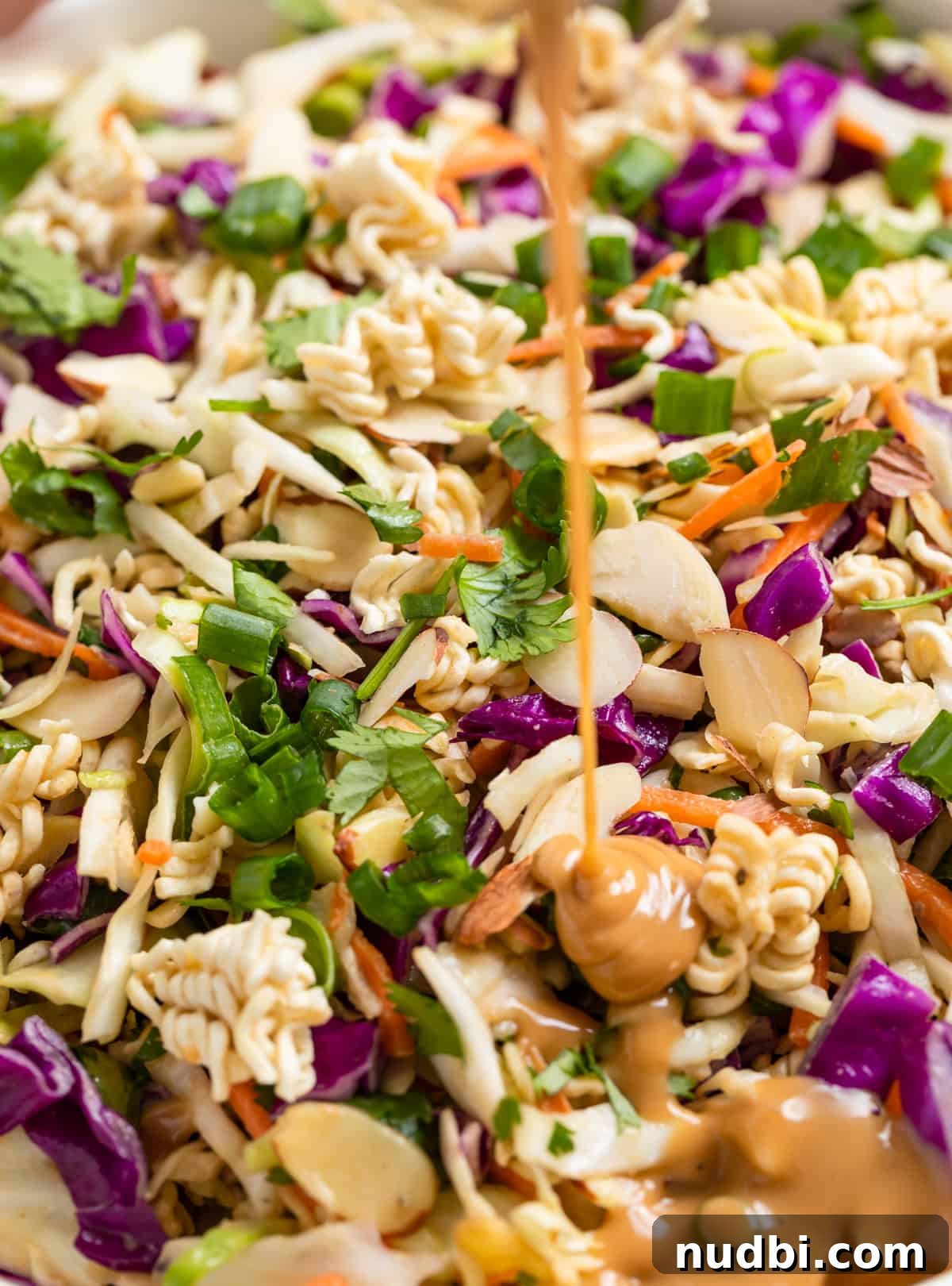 Crunchy Ramen Cabbage Salad with Creamy Peanut Dressing 4 Peanut dressing being poured onto ramen cabbage salad.
