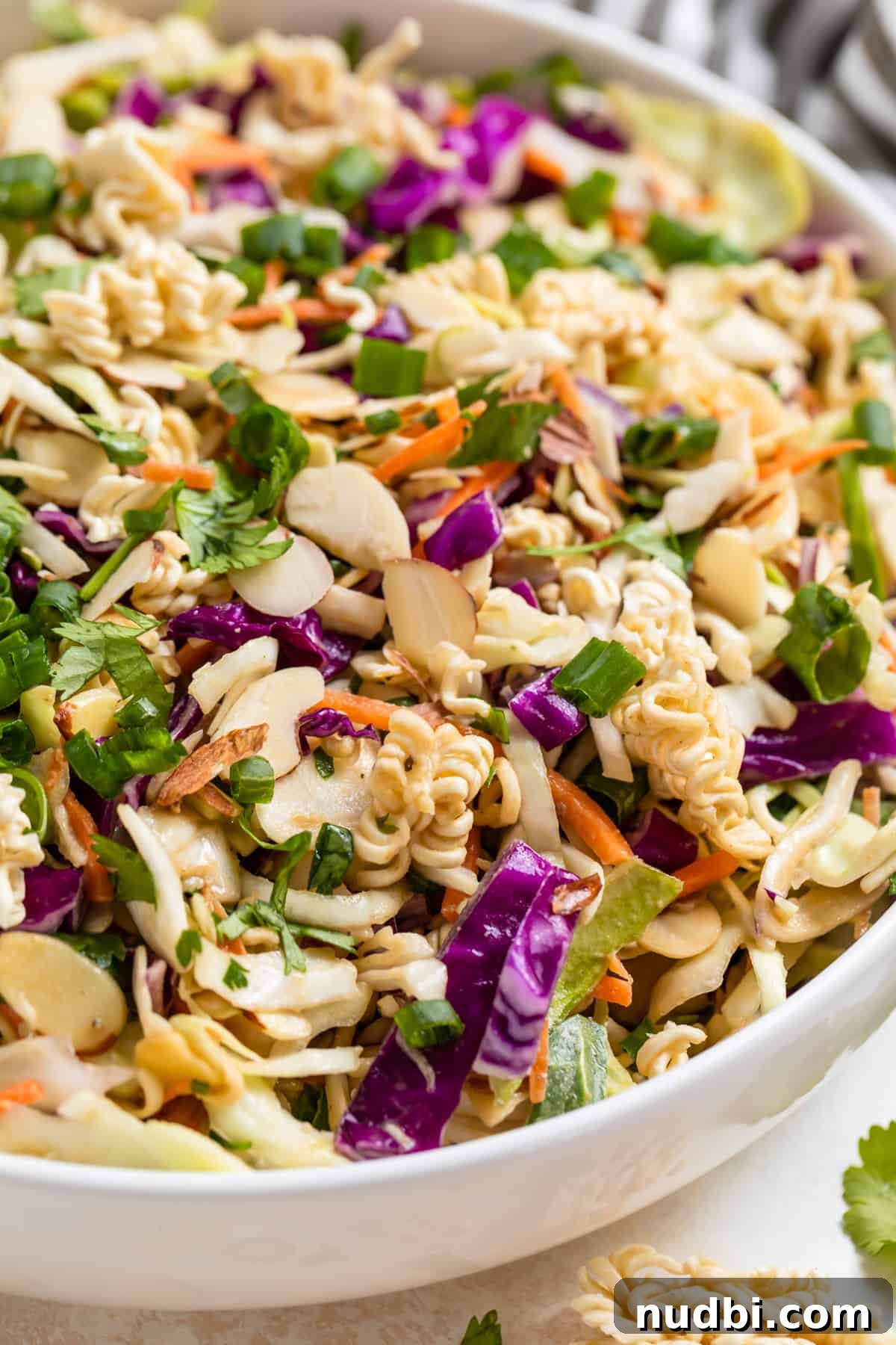 Crunchy Ramen Cabbage Salad with Creamy Peanut Dressing 5 Ramen cabbage salad with peanut dressing topped with sliced almonds, cilantro and green onion.