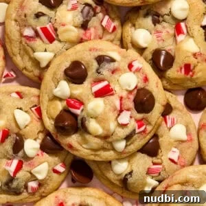 Peppermint Chocolate Chip Cookie Recipe: Festive Minty Cookies 17 Peppermint chocolate chip cookies with white and dark chocolate chips and candy canes arranged on plate.