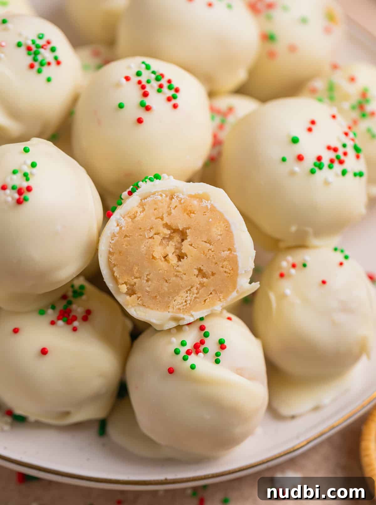 Festive Christmas Golden Oreo Truffles: Holiday Cookie Balls 3 Golden Oreo truffles on plate with bite taken out of one to show inside texture.