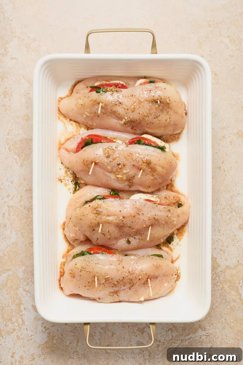 Cheesy Mozzarella-Stuffed Chicken Breast Recipe 9 Baking dish with mozzarella, tomato and basil stuffed chicken breasts before baking.