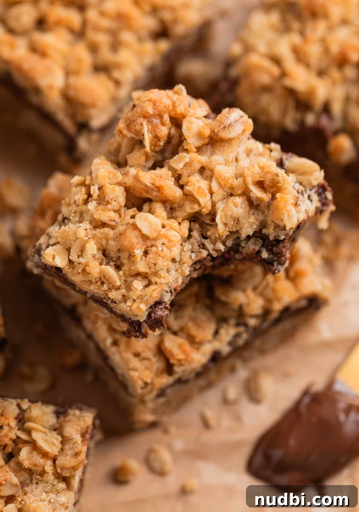 Nutella Oatmeal Bars Recipe — Chewy Hazelnut Oatmeal Squares 2 Nutella oatmeal bars stacked with bite taken out of top bar.