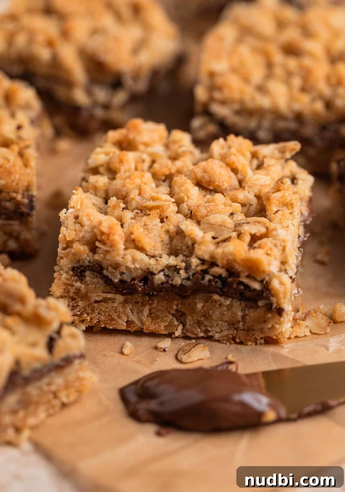 Nutella Oatmeal Bars Recipe — Chewy Hazelnut Oatmeal Squares 6 Side view of layers in nutella bars on parchment.
