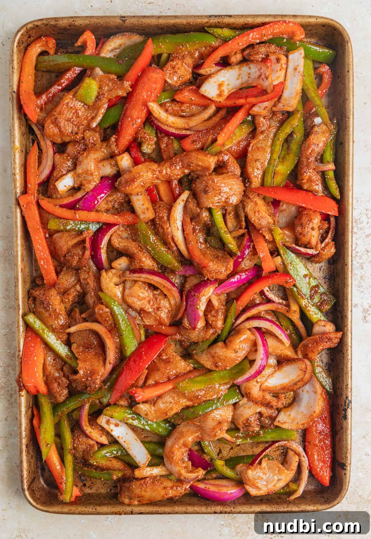 Honey-Lime Baked Chicken Fajitas Recipe for Flavorful Weeknights 7 Raw sliced chicken, peppers and onion seasoned and spread on sheet pan.