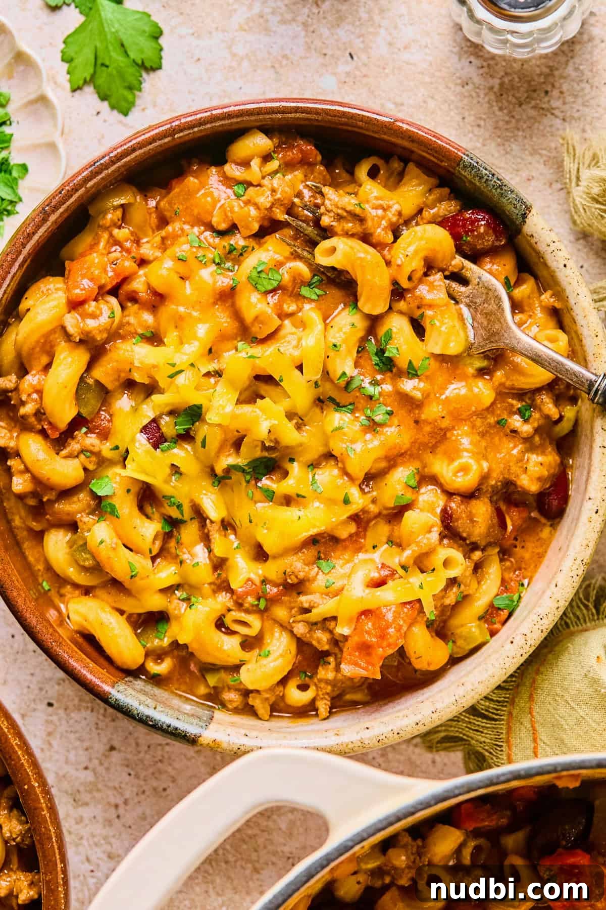 One-Pot Chili Mac: Cheesy Beef Skillet Dinner 13 Bowl of chili mac and cheese topped with shredded cheese and parsley.