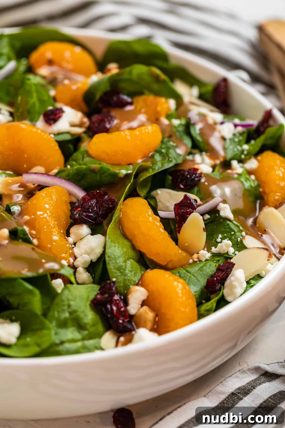 Spinach and Mandarin Salad with Honey Balsamic Vinaigrette 2 White bowl with spinach mandarin salad topped with goat cheese, cranberries, almonds and honey balsamic dressing.