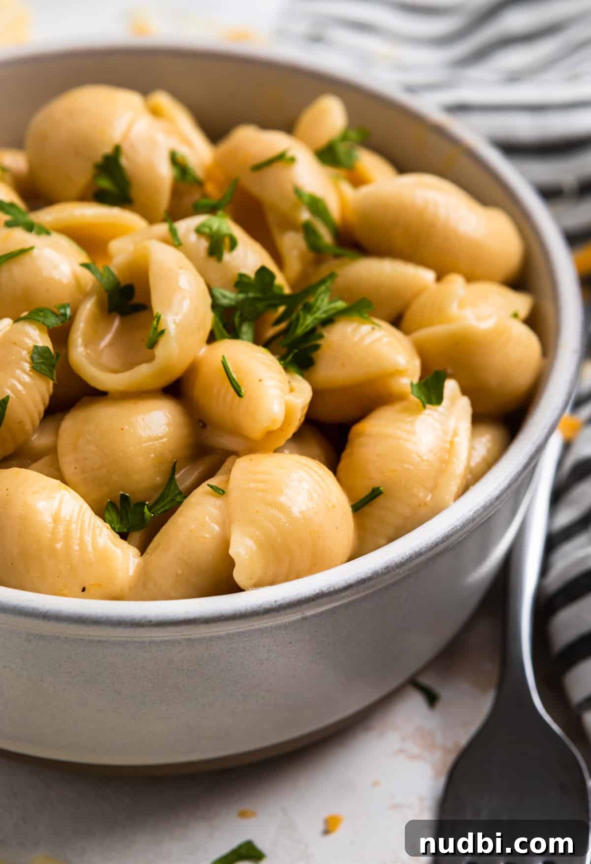 Creamy Instant Pot Mac and Cheese in 15 Minutes 6 Clay bowl with mac and cheese topped with parsley with fork beside it.