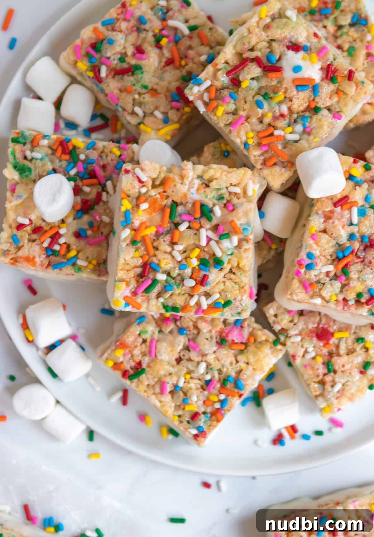 Funfetti Rice Krispie Treats Recipe for Colorful Party Snacks 6 Overhead view of funfetti rice krispie treats on plate with sprinkles and extra marshmallows.
