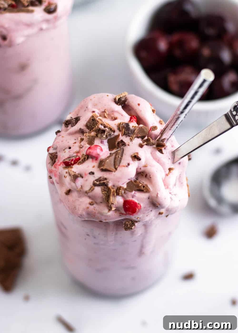 Decadent Chocolate Cherry Milkshake Recipe 2 Cherry milkshake with chocolate in and straw and spoon.