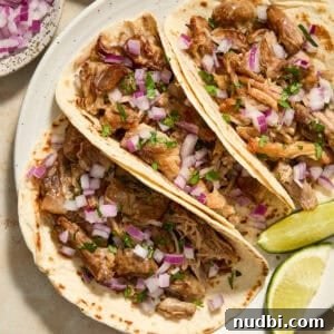 Crispy Instant Pot Carnitas Recipe for Tender, Crunchy Pork 15 Instant Pot carnitas in tortillas with onion and cilantro on white dish.