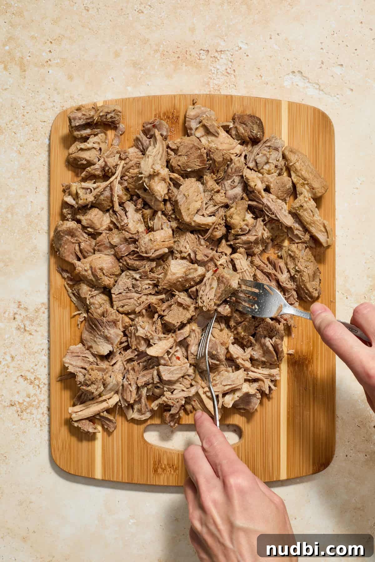 Crispy Instant Pot Carnitas Recipe for Tender, Crunchy Pork 7 Pork carnitas being shredded on cutting board with two forks.