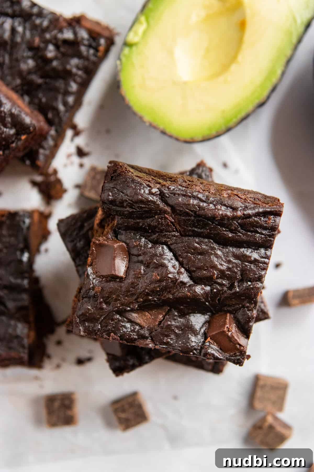 Fudgy Avocado Chocolate Chunk Brownies That Melt in Your Mouth 6 Stack of avocado brownies with cut avocado.