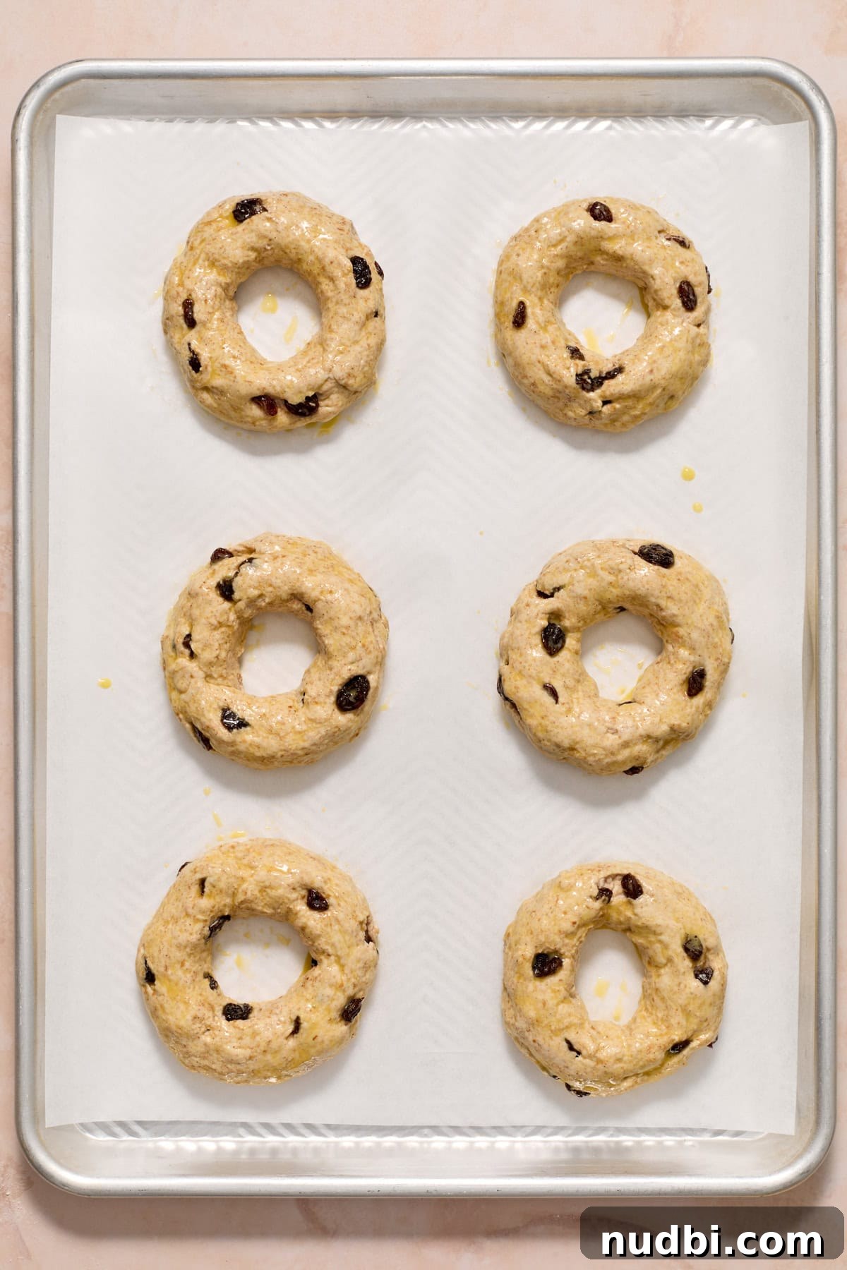 Cinnamon Raisin Bagel Recipe: Homemade Soft Chewy Bagels 10 Egg washed cinnamon raisin bagels on cookie sheet before baking.
