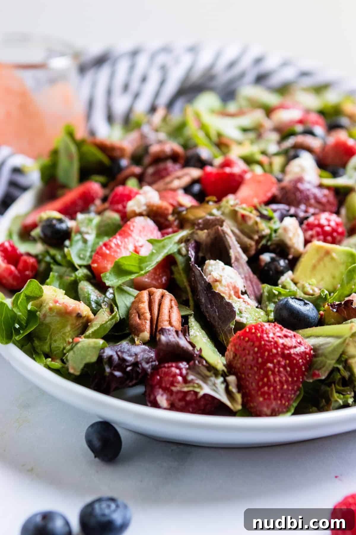 Mixed Greens with Berries and Strawberry Balsamic Dressing 2 Mixed green salad with berries on white plate with dressing.