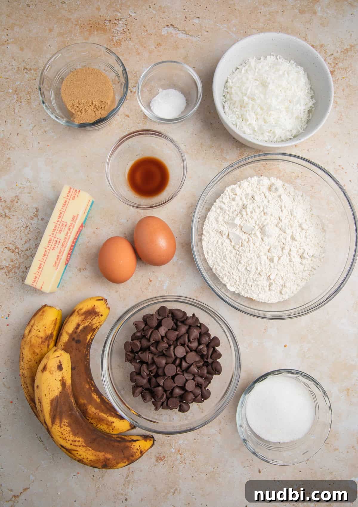 Coconut Banana Chocolate Chip Bread Recipe 4 Brown bananas, flour, sugar and other ingredients arranged on surface.