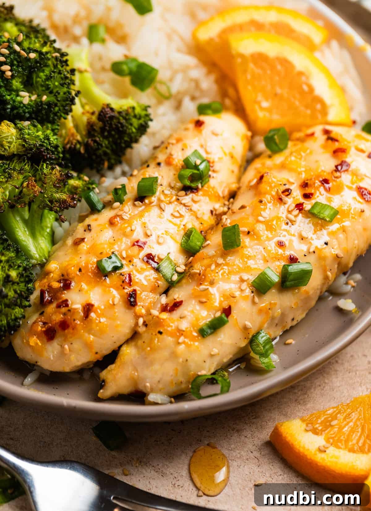 Sticky Orange Sheet Pan Chicken Dinner 2 Dish with baked orange chicken, broccoli and rice topped with sliced green onions and sesame seeds.