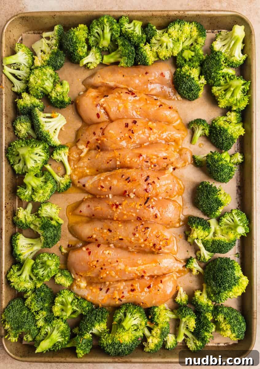 Sticky Orange Sheet Pan Chicken Dinner 9 Marinated orange chicken tenderloins and broccoli on sheet pan.