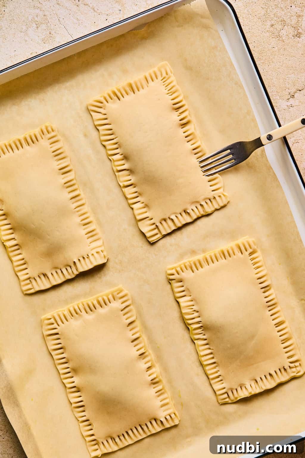 Homemade Pop-Tarts Made with Flaky Pie Crust — Sweet Breakfast Pastry 12 Fork pressing into the edges of homemade pop tarts before baking.