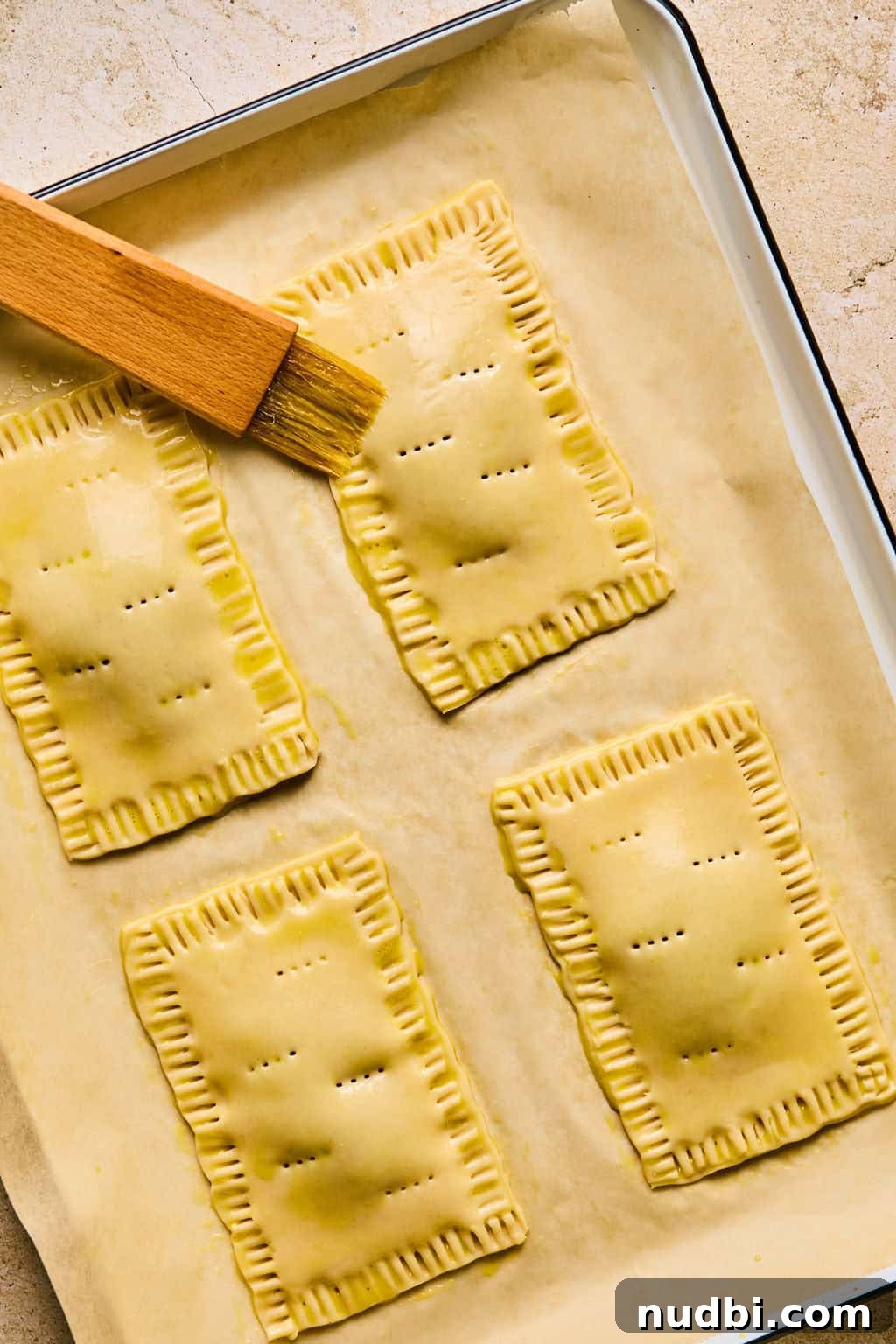 Homemade Pop-Tarts Made with Flaky Pie Crust — Sweet Breakfast Pastry 14 Egg wash being brushed on tops of pop tarts before baking.