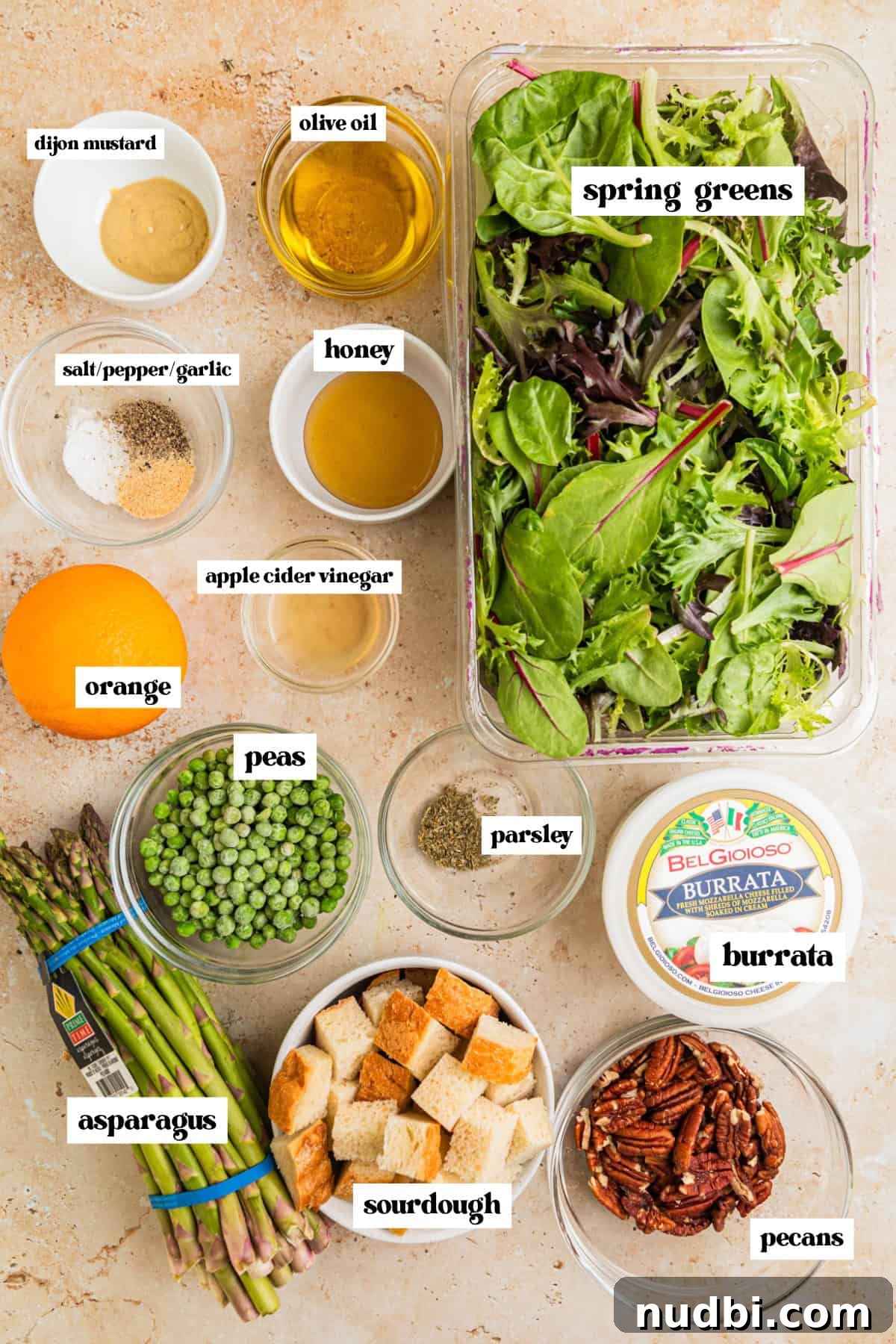 Spring Green Burrata Salad with Lemon Herb Vinaigrette 3 Mixed greens, bread cubes, burrata cheese, asparagus and other salad ingredients arranged on surface.
