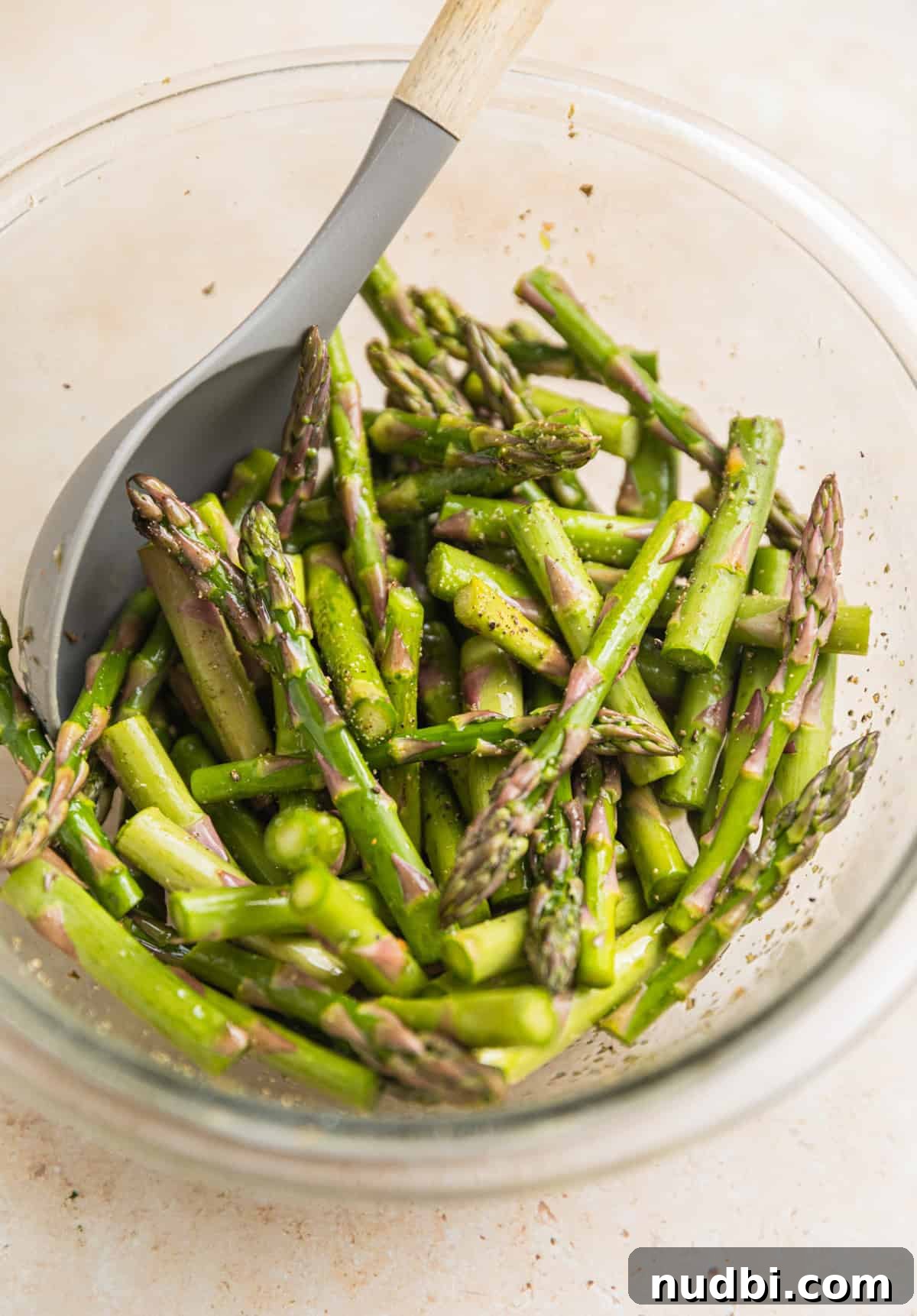 Spring Green Burrata Salad with Lemon Herb Vinaigrette 5 Asparagus pieces in bowl with spoon.