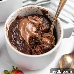 Quick Nutella Mug Cake Recipe for a Warm Chocolate Treat 7 Flourless Nutella mug cake in mug with spoon and extra dollop of Nutella.