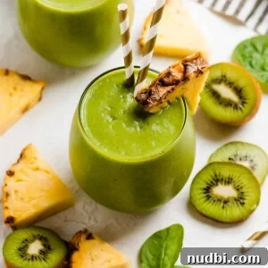Pineapple Kiwi Smoothie Recipe for Fresh Morning Energy 6 Wine glass with pineapple kiwi smoothie with two straws and sliced pineapple and kiwi surrounding.