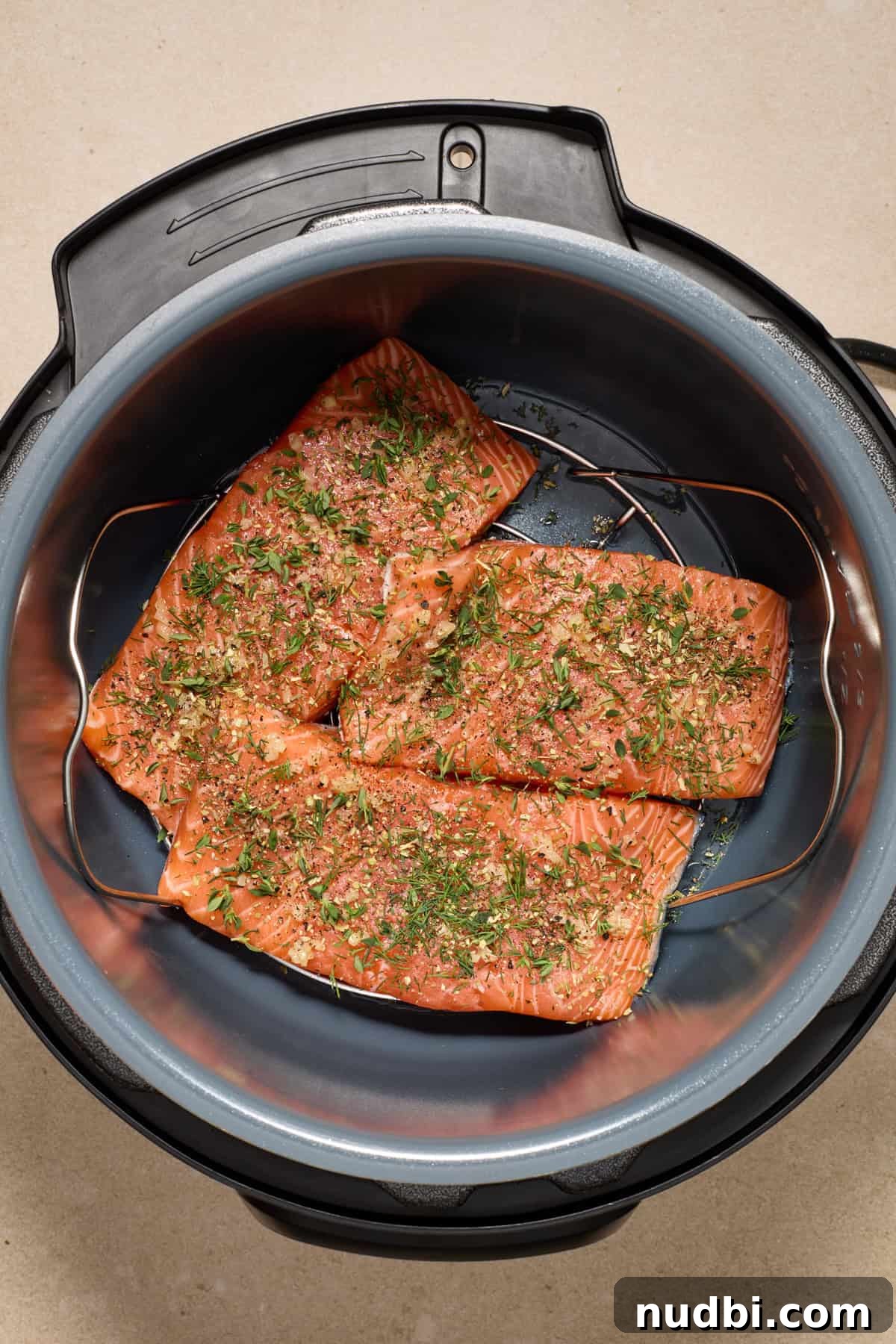 Instant Pot Butter Herb Salmon Recipe for Tender, Flaky Fish 5 Seasoned salmon filets in instant pot with fresh herbs over top.