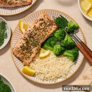 Instant Pot Butter Herb Salmon Recipe for Tender, Flaky Fish 9 Plate with herbed salmon served with broccoli and rice with lemon wedges.